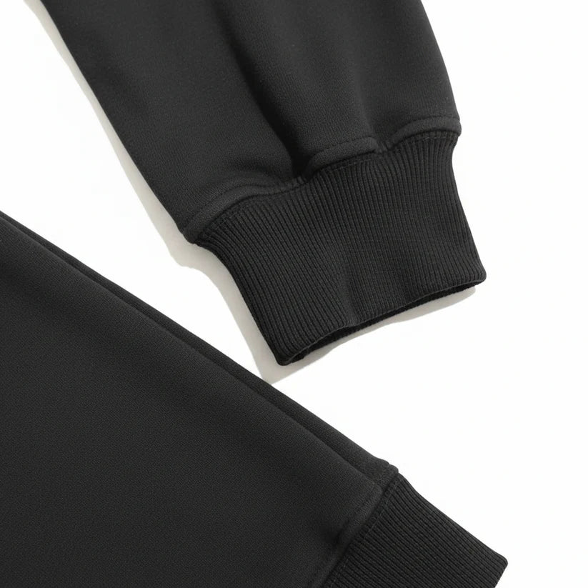 Close-up detail of a black ribbed knit garment, showing the cuff and sleeve construction on a white background.