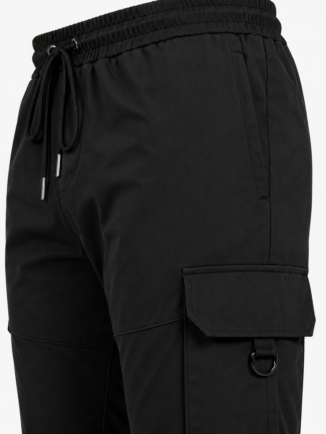 Close-up of black cargo-style shorts with an elastic drawstring waistband, side pockets, and a large flap cargo pocket on the leg.