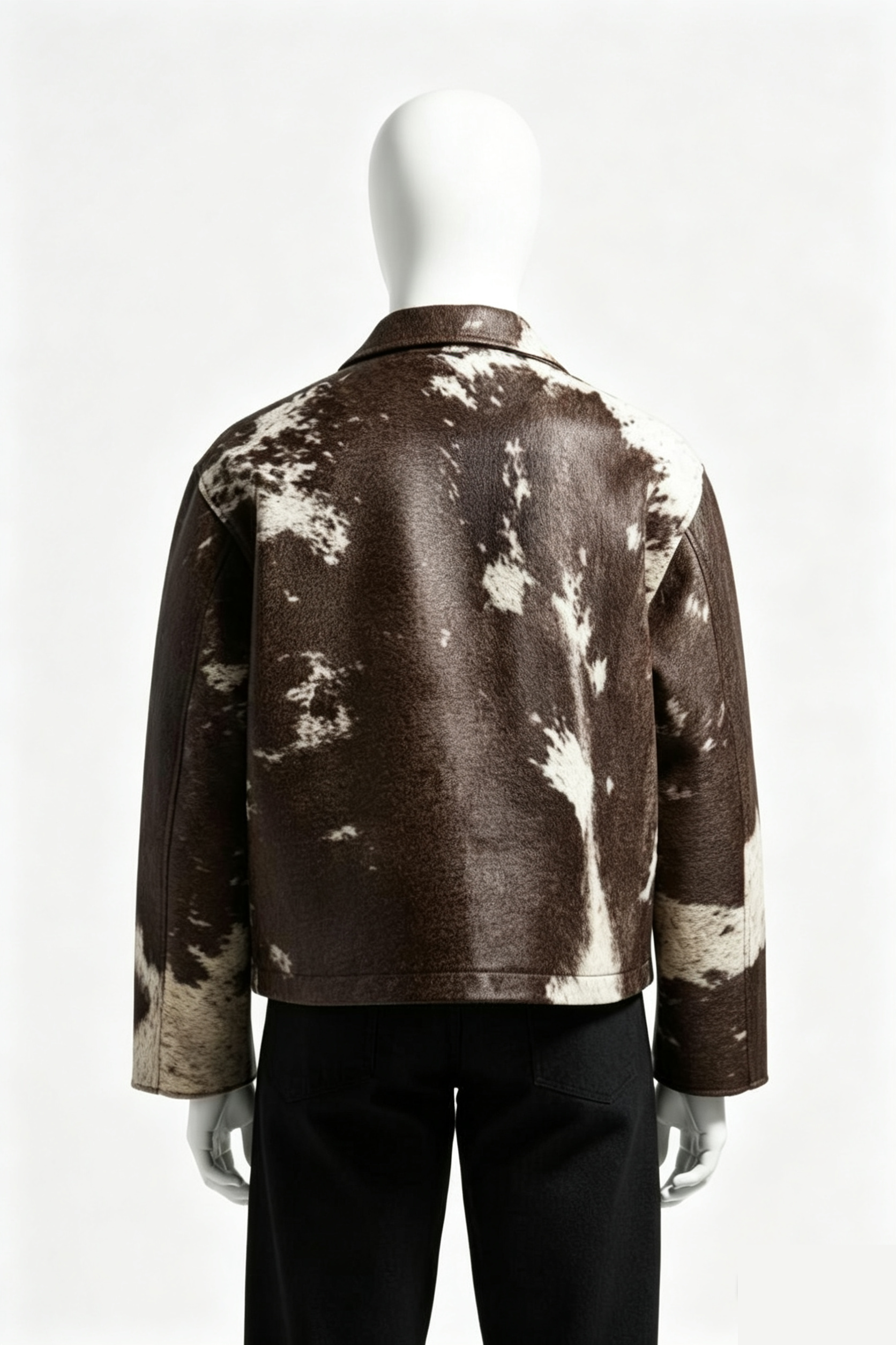 A brown leather jacket with a white cow-print pattern, shown from the back on a white mannequin against a light gray background.