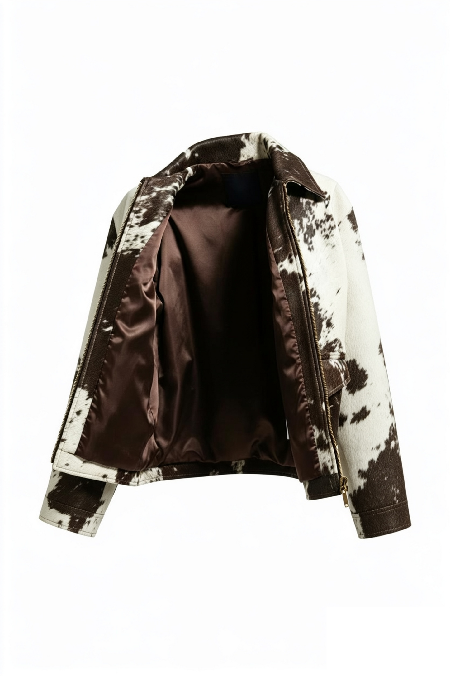 A cropped moto jacket with a brown and white cow-print pattern on the exterior and a solid dark brown satin lining, shown open against a plain white background.