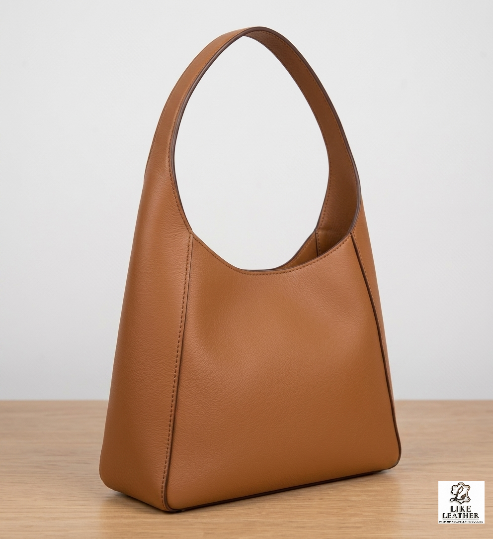 Full view of the LIKE LEATHER tan pebbled leather shoulder bag on a wooden surface for size reference.